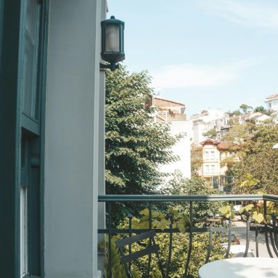 A serene balcony setting with a picturesque cityscape and lush trees.