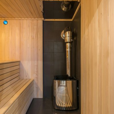 Modern wooden sauna with a sleek metal heater, showcasing luxury home interior design.